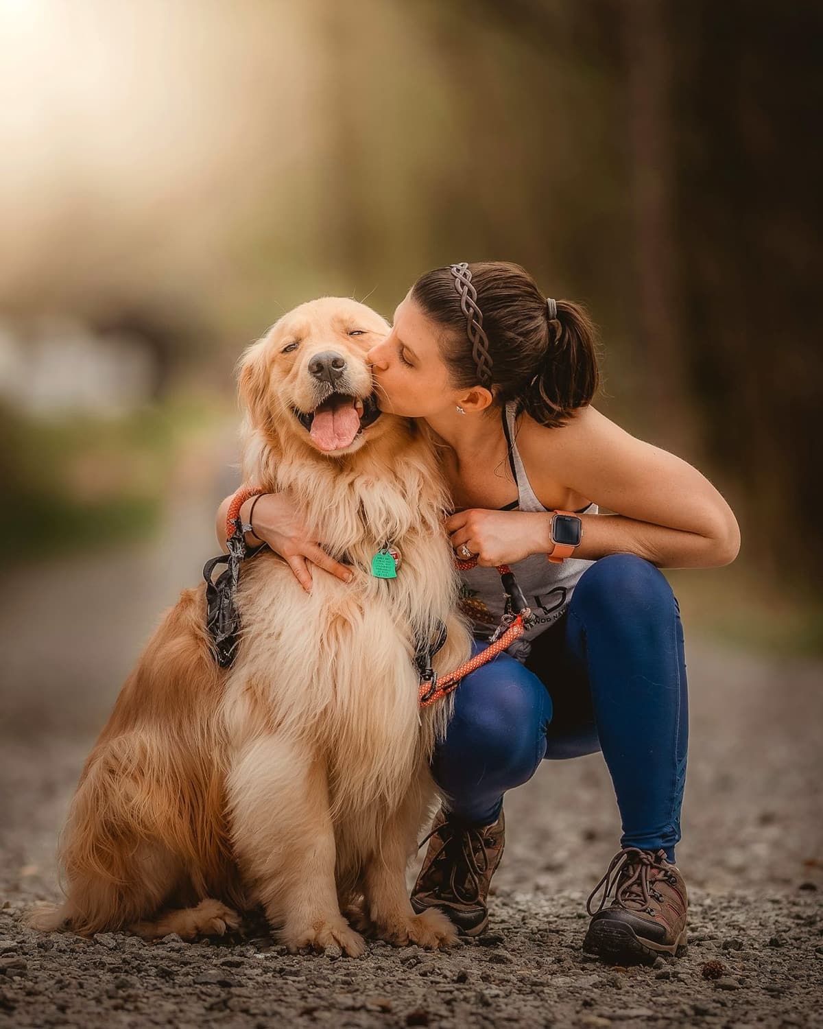 A woman kisses a golden retriever